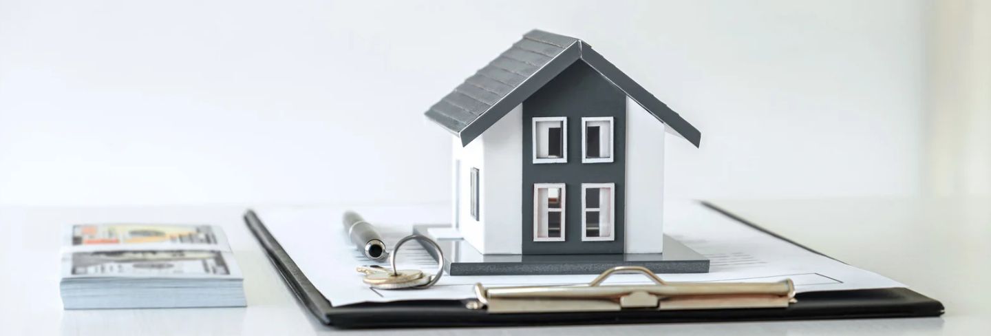 Documentos, dinero y una casa en miniatura durante el proceso de compra de una propiedad en Florida